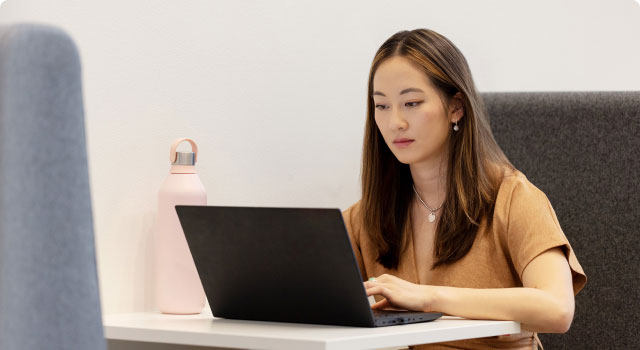 Asian woman working on a laptop at a desk